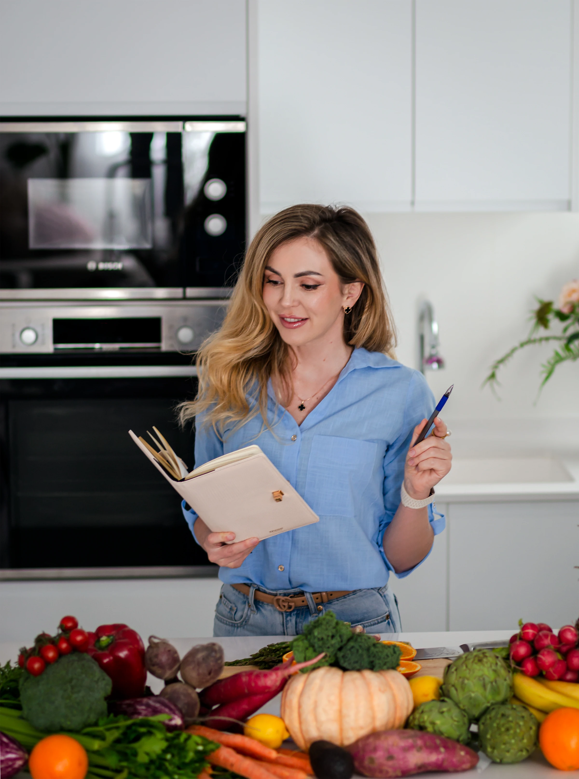 Valentyna holding a notebook in a bright kitchen